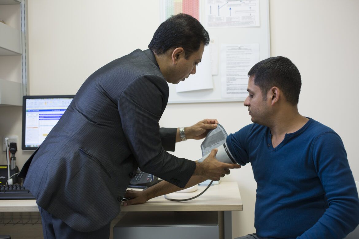 Male GP taking the blood pressure of a male patient